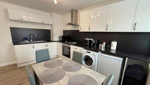 Una cocina compacta con lavadora, cafetera y tostadora.