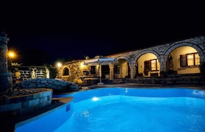 A swimming pool with stone architecture and outdoor seating. - Saltos Village Apartment - Serene Poolside Escape (Nea Propontida)