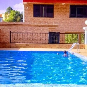 A swimming pool with a metal ladder, surrounded by a brick wall and a black metal fence. - Crestpark View Palace Apartment (Nairobi)