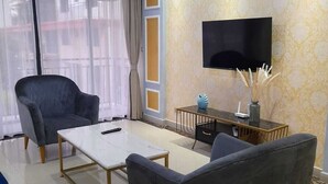 Moderni olohuone, jossa on litteänäyttöinen televisio, sohva, sohvapöytä ja koristeellinen maljakko.
