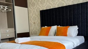 Hotellihuone, jossa on suuri sänky, vaatekaappi ja kuviollinen tapetti.