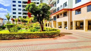 A modern hotel with a landscaped courtyard, multiple parking garages, and a prominent building with balconies. - Crestpark View Palace Apartment (Nairobi)