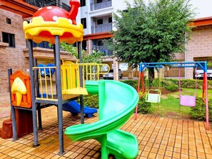 A playground with a slide, climbing structures, and swings. - Crestpark View Palace Apartment (Nairobi)