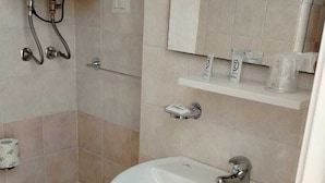 A bathroom with a toilet, bidet, sink, and a towel rack.