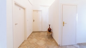 A corridor with three doors, a tiled floor, and a small table with a vase.