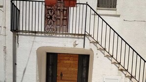 A building with a wooden door, a metal staircase, and a window with a curtain.