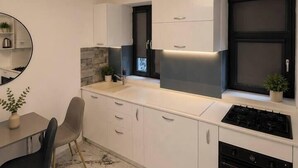 A modern kitchen with white cabinets, a black stove, and a marble floor. - Luxury Designer Studio | King Bed | Near Old Town (Bucharest)