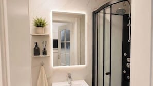 A modern bathroom with a white vanity, a glass shower enclosure, and a mirror above the sink. - Luxury Designer Studio | King Bed | Near Old Town (Bucharest)