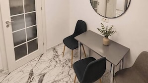 A room with a white door, a round mirror, a grey table, and two chairs. - Luxury Designer Studio | King Bed | Near Old Town (Bucharest)