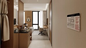 Habitación de hotel con escritorio, silla y un mapa de salidas de emergencia en la pared.