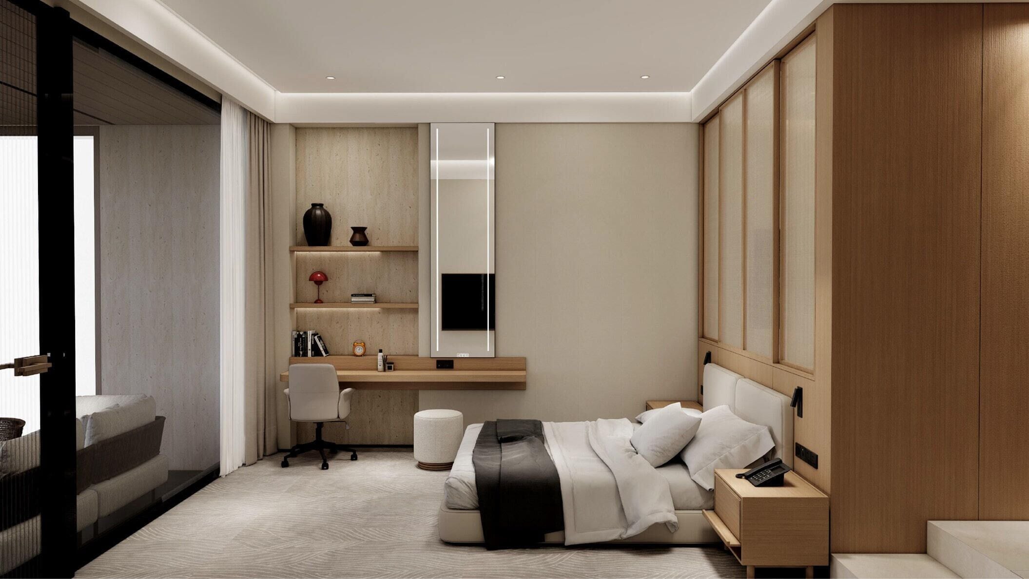 A modern hotel room with a bed, bedside table, desk, chair, and a large mirror.