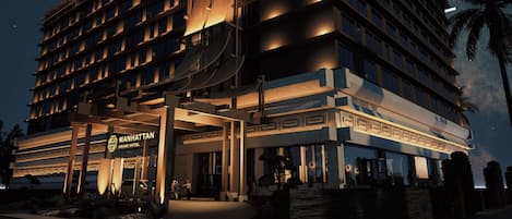 A multi-story hotel with a grand entrance, a visible sign for the Manhattan Grand Hotel, and a palm tree in the foreground.