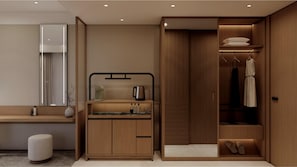 A modern bathroom with a vanity, mirror, and a walk-in closet with hanging clothes and shoes.