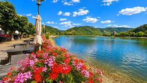 Vista al río con zona de comedor, asientos al aire libre e iglesia al fondo.