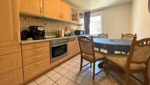 A kitchen with wooden cabinets, a coffee maker, a microwave, and a dining table with chairs. - Spacious apartment with balcony (Boppard)