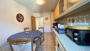 Una cocina compacta con una mesa de comedor, sillas, microondas y un lavamanos.