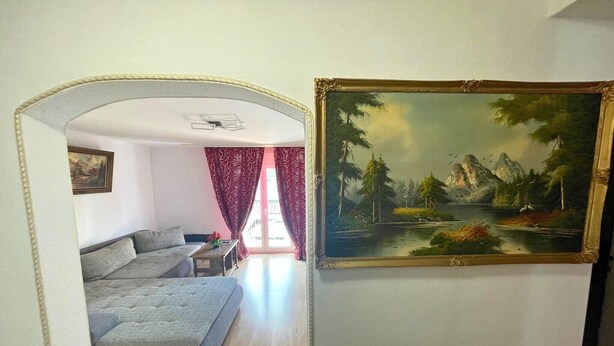 A room with a sofa, a painting, and a window with curtains. - Spacious apartment with balcony (Boppard)