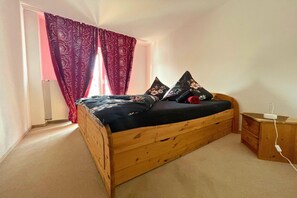 A single bed with a wooden frame, a small bedside table, and a power outlet. - Spacious apartment with balcony (Boppard)