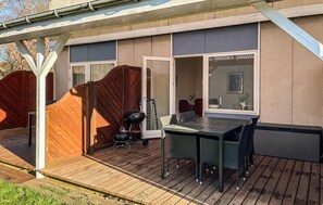 An outdoor patio with a table and chairs, a grill, and a sliding glass door leading to an interior space. - Beautiful apartment in Nexø with sauna (Nexø)