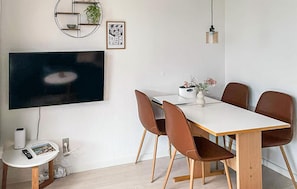 Ein Essbereich mit an der Wand montiertem Fernseher, einer runden Ablage mit Pflanze und einem gerahmten Bild.