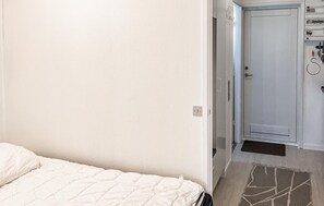 A hotel room with a bed, a door, and a small control panel with a power outlet. - Beautiful apartment in Nexø with sauna (Nexø)