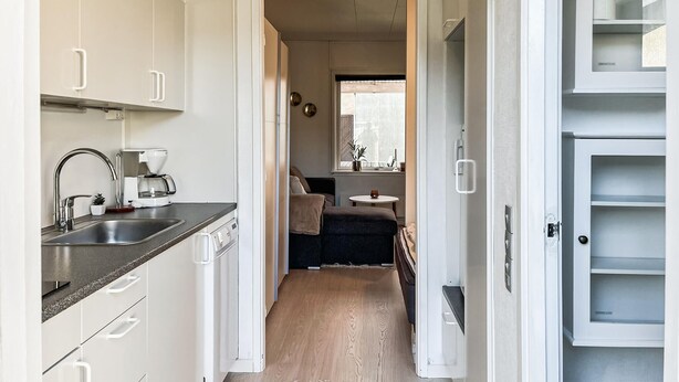 Een kleine keuken met een spoelbak, koffiezetapparaat en kastjes.