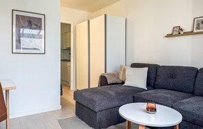 A modern living room with a grey sectional sofa, a small round table, and a white coffee table. - Beautiful apartment in Nexø with sauna (Nexø)