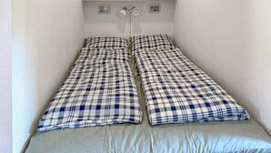 En seng med to madrasser og et ternet sengetæppe.