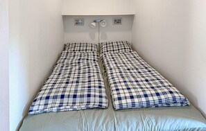 Ein Doppelbett mit kariertem Überwurf und einer hellen Matratze.