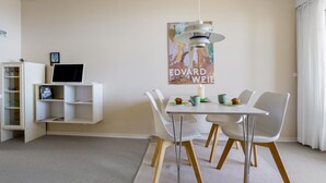 A modern dining area with a white table, chairs, and a hanging light fixture. - Cozy apartment in Allinge with WiFi (Allinge)