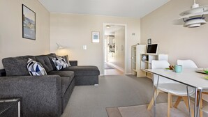 A modern living room with a grey sofa, a dining table with chairs, and a kitchen area in the background. - Cozy apartment in Allinge with WiFi (Allinge)