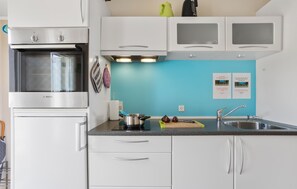 A kitchen with a Bosch oven, white cabinets, a blue wall, and a sink. - Cozy apartment in Allinge with WiFi (Allinge)