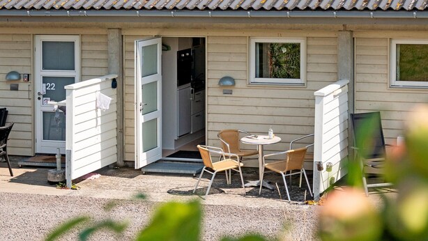 A single-story building with a tiled roof, a front door, and a small patio area with a table and two chairs. - Cozy apartment in Allinge with WiFi (Allinge)