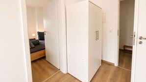 A hotel room with a bed, bedside table, and a door leading to another room. - Zum Rheinberg – Balcony Suite (Braubach)