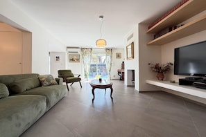 A modern living room with a sofa, a coffee table, and a television. - Charming Villa for 6 in Agde (Agde)