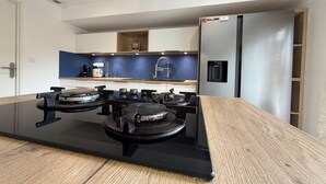 A modern kitchen with a central island stove, a stainless steel refrigerator, and a blue backsplash. - Charming Villa for 6 in Agde (Agde)