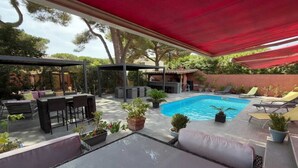 A covered outdoor area with a pool, seating, and potted plants. - Charming Villa for 6 in Agde (Agde)