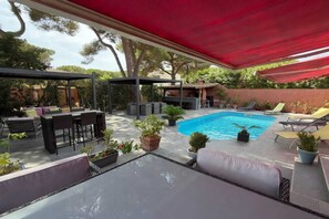 Ein überdachter Außenbereich mit Pool, Sitzgelegenheiten und Topfpflanzen.