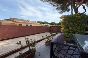 Eine Dachterrasse mit Sitzgelegenheit, Kübelpflanzen und Blick auf Gebäude im Hintergrund.