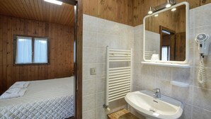 Una habitación con cama, un radiador blanco, un lavamanos y un espejo.