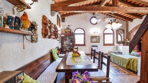 Uma sala de jantar com uma mesa de madeira, bancos e um candelabro.