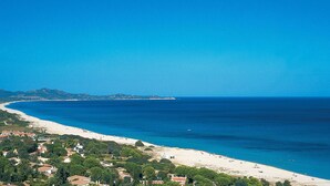 A coastal view with a beach, clear blue sky, and a distant mountain range. - Stunning home in Costa Rei with WiFi (Costa Rei)
