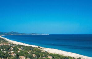 Blick auf die Küste mit Strand, blauem Himmel und fernen Bergen.