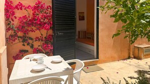 An outdoor dining area with a table and chairs, a sliding door, and a wall adorned with pink flowers. - Stunning home in Costa Rei with WiFi (Costa Rei)