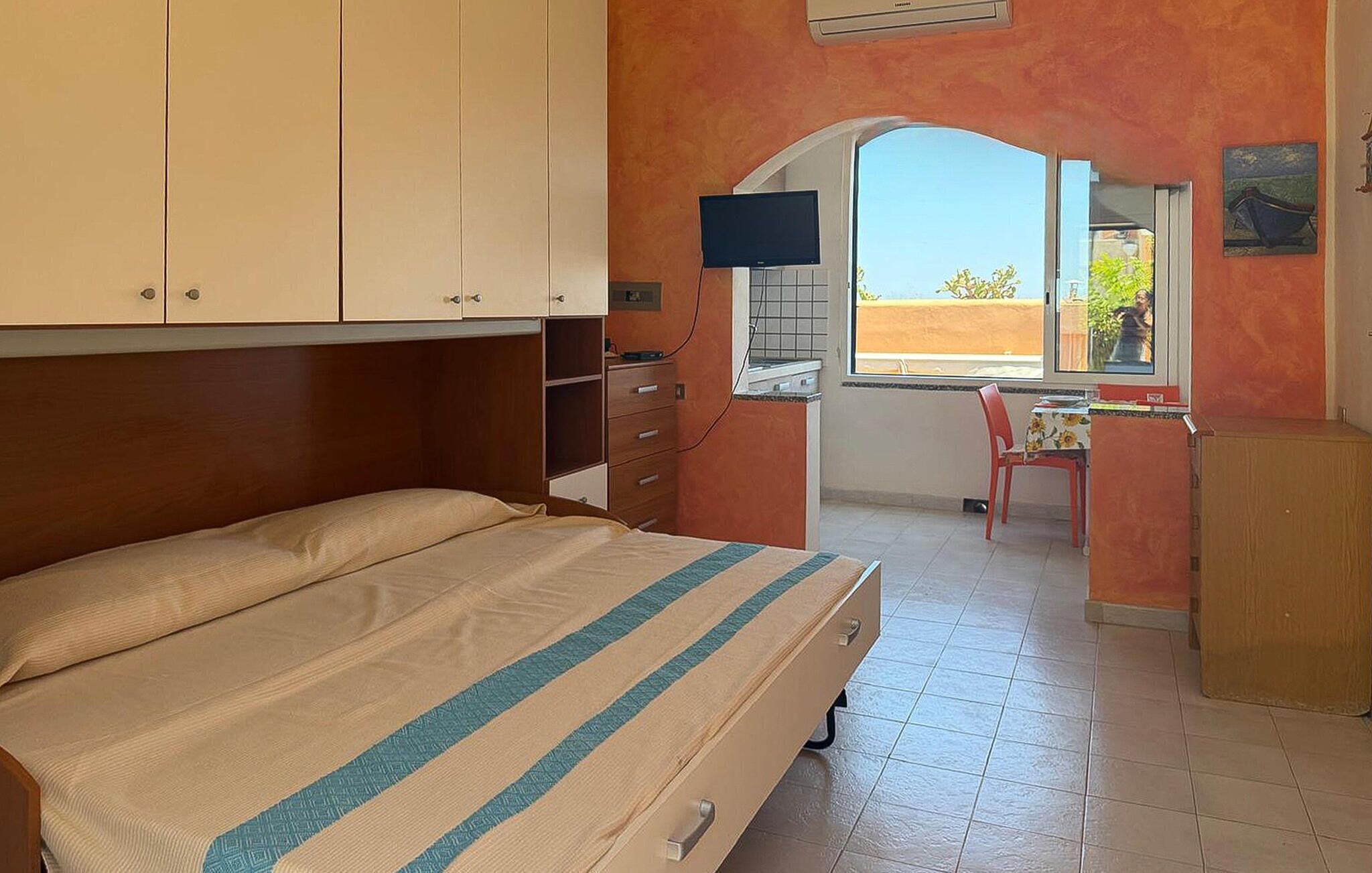 Une chambre à coucher avec un lit, un bureau, une chaise et une fenêtre donnant sur un beau paysage.