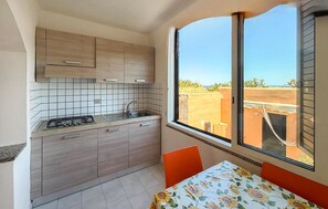 A compact kitchen with a gas stove, sink, and wooden cabinets. A window provides a view of the outside. - Stunning home in Costa Rei with WiFi (Costa Rei)