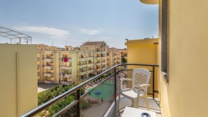 Ein Balkon mit Blick auf einen Wohnkomplex, einem Metallgeländer und einem weißen Stuhl.