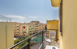 Ein Balkon mit Blick auf einen Wohnkomplex, einem Metallgeländer und einem weißen Stuhl.