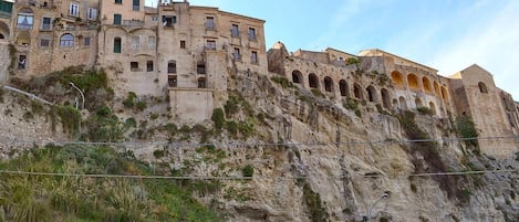 Un edificio histórico con varios balcones y ventanas de arco, ubicado en un acantilado pronunciado.