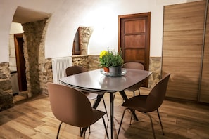 A dining area with a table and chairs, a potted plant with yellow flowers, and a stone wall.
